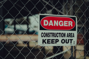 A yellow danger sign reading construction area keep out posted at a secured construction site perimeter