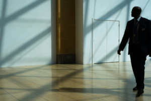 A suited security officer walking through the interior corridor of a commercial building during a patrol