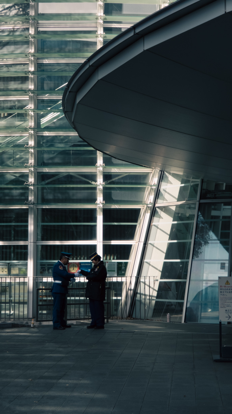Two uniformed security officers standing guard in front of a commercial building entrance