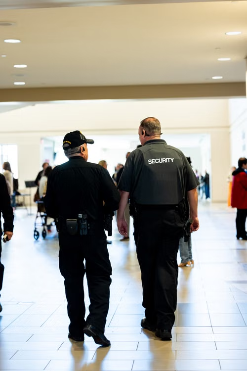Two uniformed security officers conducting an interior patrol inside a busy shopping mall
